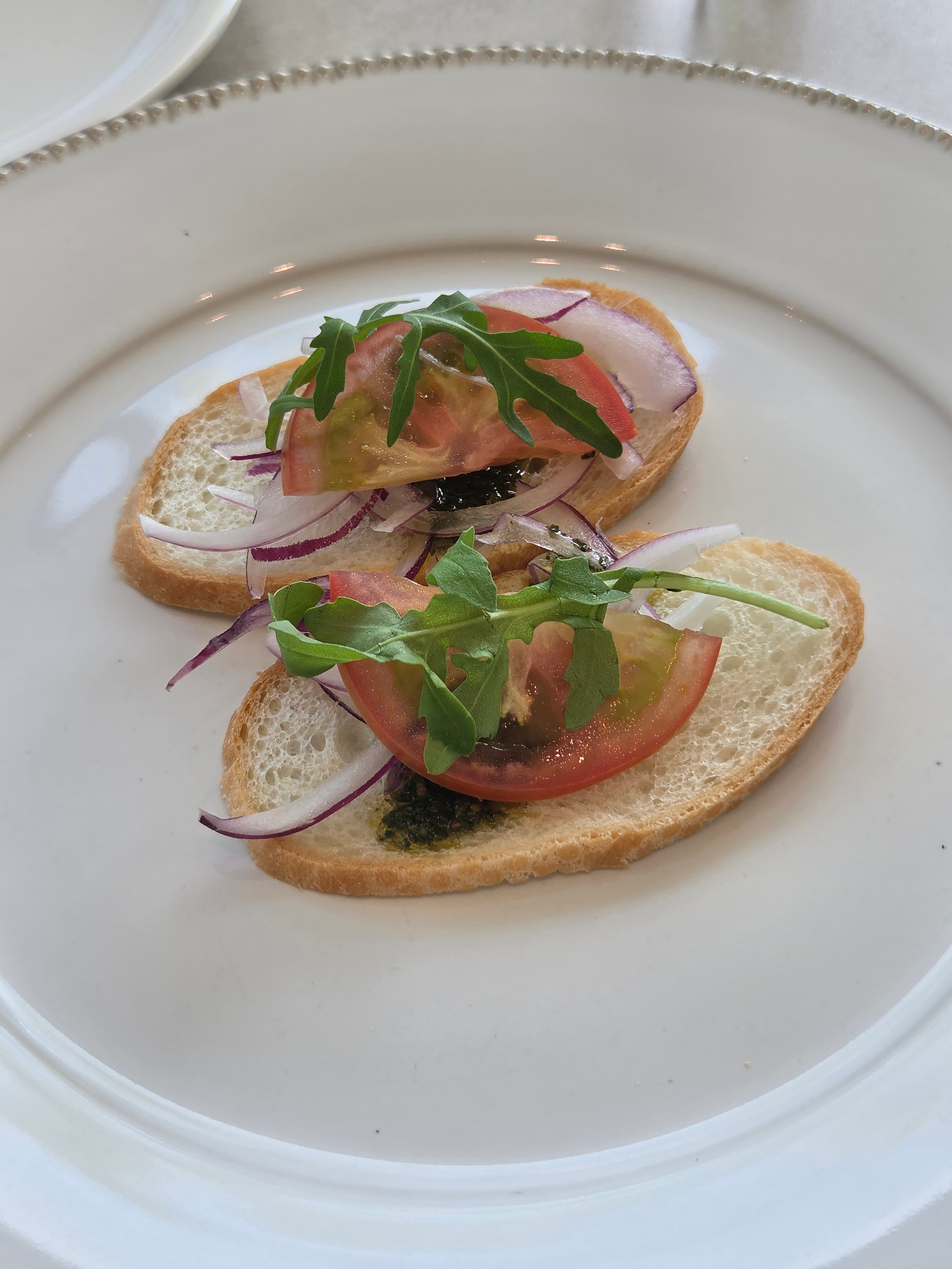 Complimentary bruschetta starter at Seasoner Jeonju with tomato, red onion, arugula and a balsamic-herb drizzle on toasted baguette